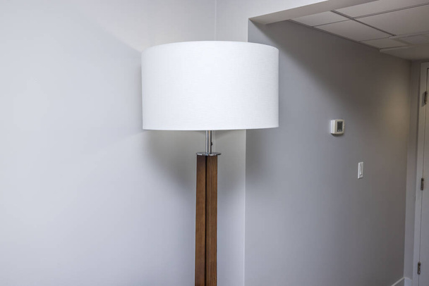 Close-up view of white floor lamp in hotel room on white wall background. - Photo, Image
