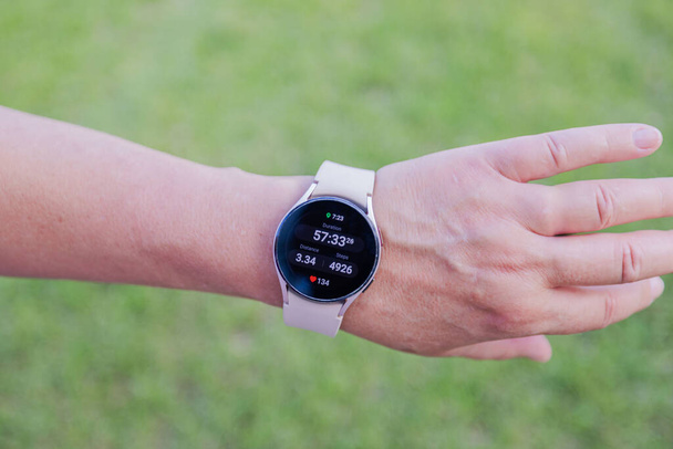 Közelkép a női kéz díszített smart watch megjelenítő nagy lépés számít elmosódott zöld háttér. - Fotó, kép