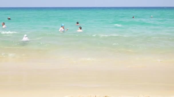 Многие отдыхают на пляже и занимаются водными видами спорта под солнечным светом ясного голубого неба, отдых на острове Фукет в 4K видео - Кадры, видео
