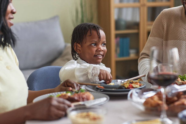 アフリカの少女がテーブルに座り,家族と一緒に夕食をとる - 写真・画像
