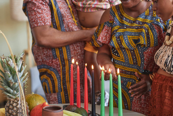 Lähikuva Afrikkalainen perhe kansallisissa puvuissa sytyttää kynttilöitä juhlia Kwanzaa loma - Valokuva, kuva