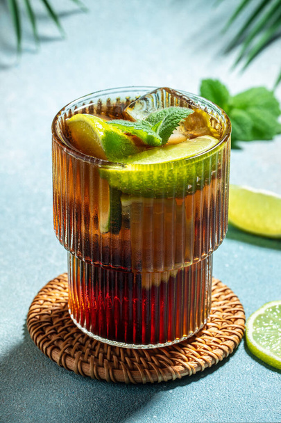 Cuba Libre met rum, cola, munt en limoen in het glas op een lichte achtergrond, verticaal beeld. Bovenaanzicht. plaats voor tekst, - Foto, afbeelding