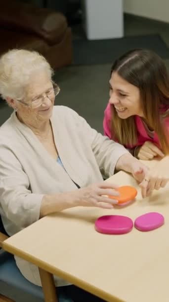 看護の家で毎日のシーンのトップビュービデオ.介護者は老婦人を笑わせる. - 映像、動画