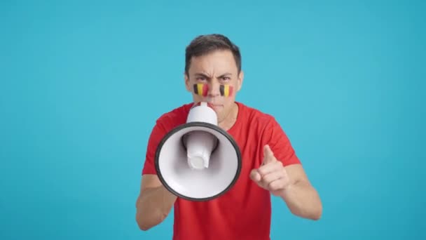 Βίντεο σε στούντιο με chroma ενός άνδρα με μια βελγική σημαία ζωγραφισμένο στο πρόσωπό του συσπειρώνει τα πλήθη χρησιμοποιώντας ένα μεγάφωνο - Πλάνα, βίντεο