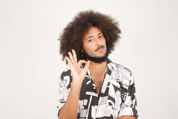 portrait of handsome young expressive mixed race man with curly hair isolated on white showing okay sign - Foto, Bild