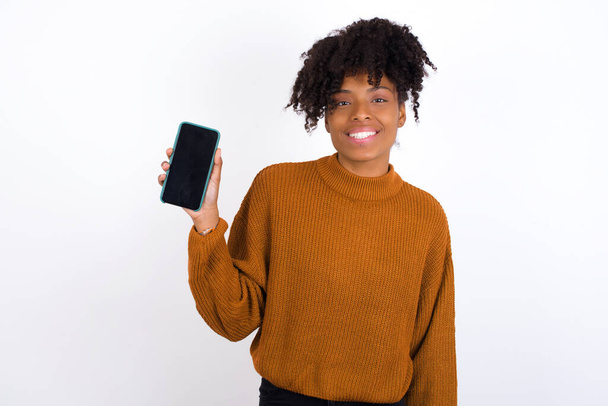 Uśmiechnięta młoda kobieta pokazuje pusty ekran telefonu. Koncepcja reklamy i komunikacji. - Zdjęcie, obraz