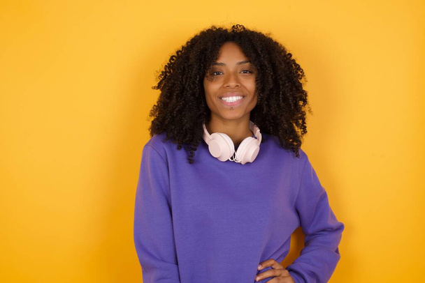 portré fiatal kifejező afro-amerikai nő fejhallgató sárga háttér - Fotó, kép
