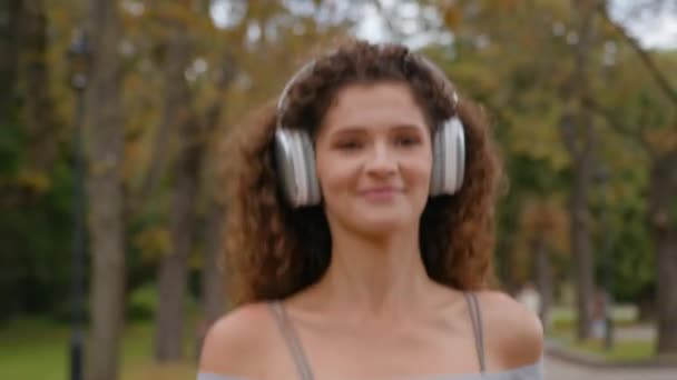 Gelukkig jong Kaukasische vrouw runner jogger meisje sport vrouw run running park buiten genieten muziek luisteren lied in hoofdtelefoon glimlachen joggen in de stad activiteit training gezonde levensstijl fitness - Video