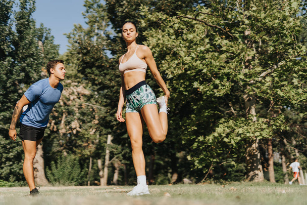 Kaukázusi sportolók edzenek a parkban, nyújtózkodnak és bemelegítenek az aktív foglalkozásuk előtt. Az egészséges életmód motiválta őket, kitartóan felkészülnek a fitnesz rutinra.. - Fotó, kép