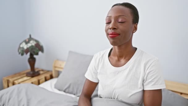 Iloinen afroamerikkalainen nainen makaa sängyssä kotona, kädet rinnassa kiitollisena eleenä, säteilevä terveys ja rauha. niin paljon enemmän kuin kuva, se on muotokuva kukoistava elämäntapa. - Materiaali, video