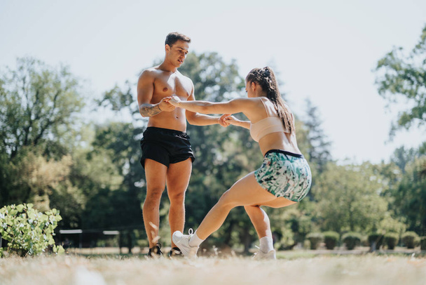 Professionele sporters bereiden zich voor op lichaamsbeweging in de buitenlucht in een zonnig park. Ze beoefenen recreatieve sporten en genieten van een uitdagende fitness routine in een natuurlijke omgeving. - Foto, afbeelding