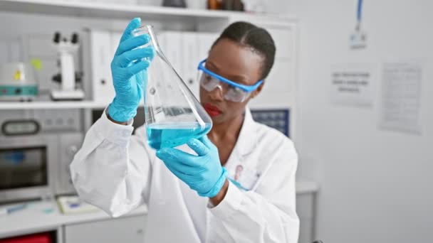 Εργατική και όμορφη Αφροαμερικανή γυναίκα επιστήμονας ανάλυση δοκιμαστικό σωλήνα σε ένα εργαστήριο υψηλής τεχνολογίας - Πλάνα, βίντεο