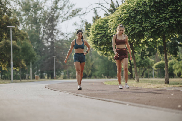 Дві підходящі дівчата бігають на відкритому повітрі в зеленому парку, надихаючи здоровий спосіб життя та фітнес на відкритому повітрі. - Фото, зображення
