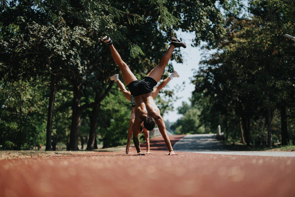 Aktywni, kaukascy sportowcy ćwiczą Cartwheel w parku w słoneczny dzień - Zdjęcie, obraz