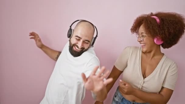 Schöne Paar, voller Liebe, genießen einen Tanz zusammen, während Musik hören, über einem kühlen rosa isolierten Hintergrund - Filmmaterial, Video