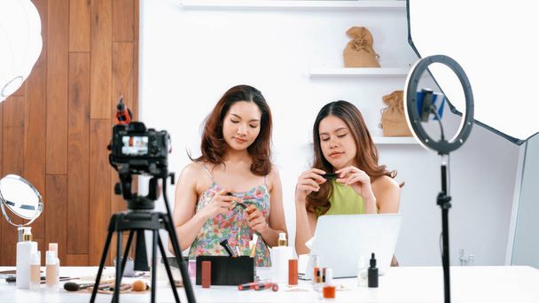 Влиятельная азиатка снимает в прямом эфире видео обзора vlog макияж в самых социальных сетях или блогах. Счастливая молодая девушка с освещением студии косметики для маркетинговой сессии трансляции онлайн - Фото, изображение