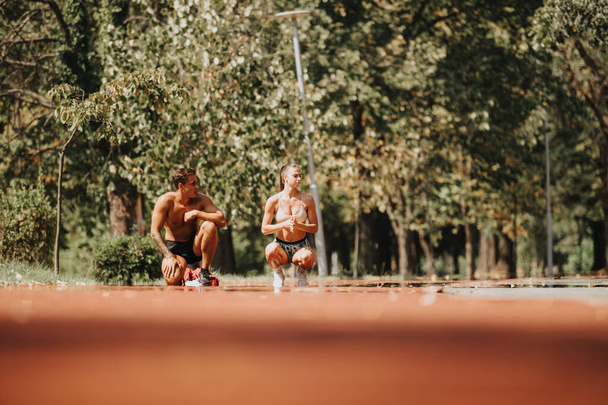 Το αθλητικό ζευγάρι και οι φίλοι του αθλητισμού προπονούνται και τρέχουν στο πάρκο με αλεξίπτωτο το ηλιόλουστο καλοκαίρι, πασχίζοντας για ένα καλύτερο σχήμα σώματος και κίνητρο φυσικής κατάστασης.. - Φωτογραφία, εικόνα