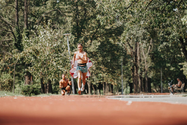 Καυκάσιοι αθλητές τρέχουν σε ένα πάρκο, προπονούμενοι μαζί για καλύτερο σχήμα σώματος και ισχυρότερους μυς. Απολαμβάνοντας ηλιόλουστες υπαίθριες προπονήσεις και παρακινώντας ο ένας τον άλλον για θετικά αποτελέσματα. - Φωτογραφία, εικόνα
