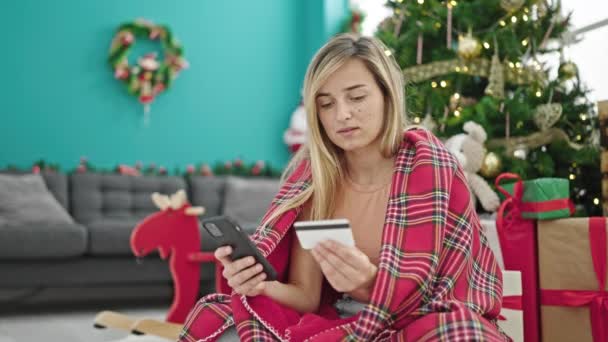 Nuori blondi nainen tekee e-ostoksia juhlii joulua kotona - Materiaali, video