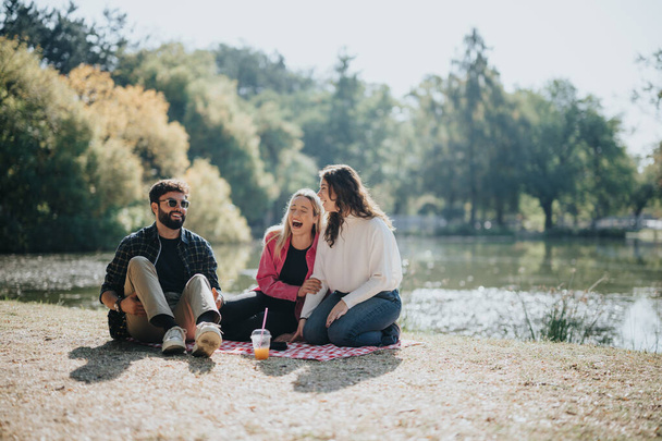 Junge Freunde treffen sich in einem Stadtpark, genießen einen unbeschwerten sonnigen Tag und unterhalten sich. Die grüne Umgebung trägt zu ihrer spielerischen und positiven Energie bei und schafft eine fröhliche Atmosphäre. - Foto, Bild