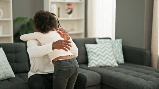 Африканський американський батько і дочка посміхаються впевнено обіймають один одного сидячи на дивані вдома - Кадри, відео