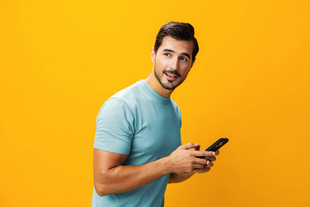 Muž usmívající se studio telefon kyberprostor žlutý životní styl brýle překvapení prostor šťastný zpráva smartphone kopie portrét telefon ukazující obchodní komunikační technologie mobilní - Fotografie, Obrázek