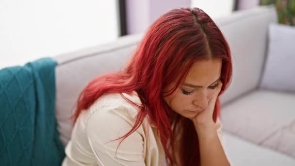 Mooie jonge Ierse roodharige vrouw, binnen ontspannen op haar woonkamer bank thuis, zorgen geëtst op haar gezicht, uitademen verdriet en twijfel - een portret van volwassen eenzaamheid - Video
