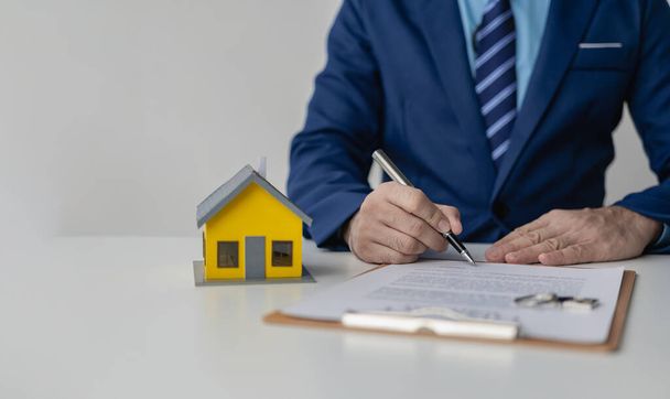 Immobilienmakler oder Makler arbeiten mit Dokumenten, Hypothekenverträgen, Darlehensideen und dem Kauf eigener Immobilien. Nahaufnahme eines kleinen Musterhauses - Foto, Bild