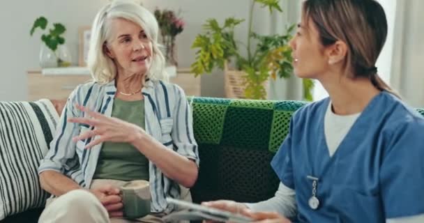 Elderly, woman and nurse with conversation for consulting, communication and discussion for healthcare on sofa. Senior, person and caregiver with tablet and consultation for health, report or coffee. - Séquence, vidéo