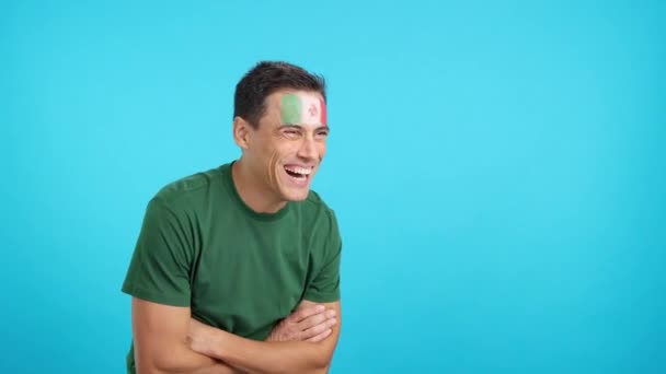 Video in studio con croma di un uomo felice con bandiera messicana dipinta sul viso guardando dall'altra parte lo spazio di copia in bianco - Filmati, video