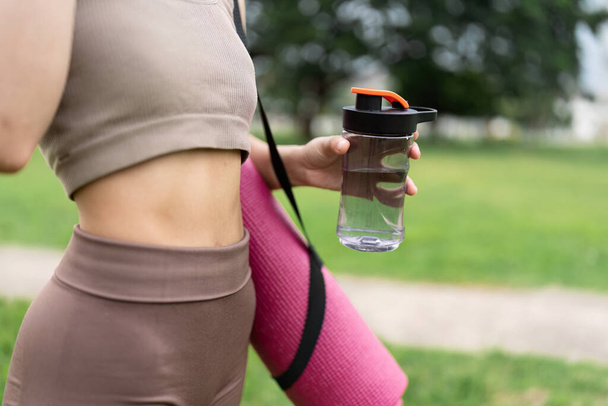 Fitness vrouw met waterfles na joggen in park. - Foto, afbeelding