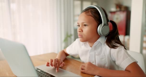 Meisje, laptop en onderwijs met koptelefoon, typen en focus voor studie, ontwikkeling en thuisschool. Kind student, computer en audio-tech e-learning met mindset, luisteren en assessment in huis. - Video