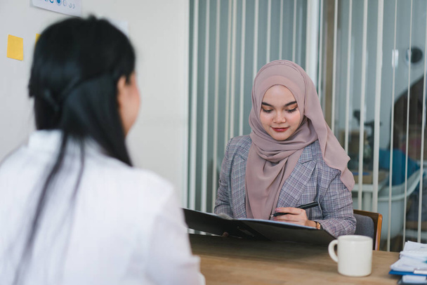 Reclutamiento musulmán amistoso Gerente de Recursos Humanos entrevistando a una joven en la sala de juntas de la oficina. Concepto de carrera y contratación. - Foto, Imagen