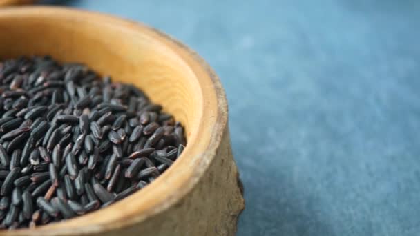 Granos de arroz negro en un tazón de madera  - Imágenes, Vídeo
