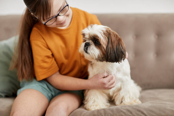 Portré aranyos lány Down-szindróma játszik a kis kutya, miközben ül a kanapén együtt, másolja tér - Fotó, kép