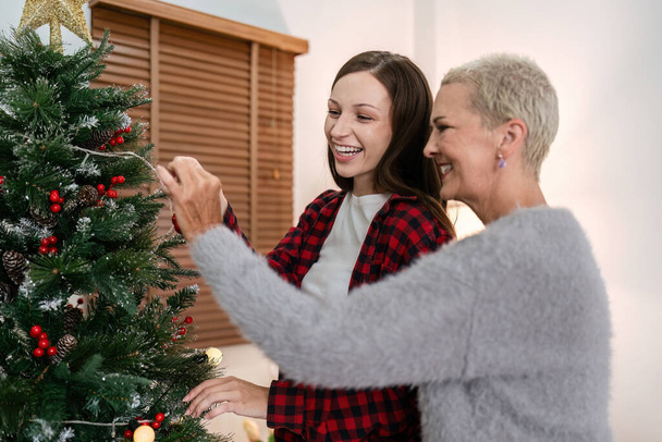 Daughter and mother caucasian decorate Christmas tree to prepare for familys Christmas Day. - Photo, Image