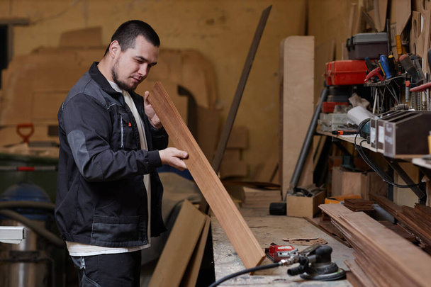 Widok z boku portret mężczyzny badającego deski drewniane w warsztacie, przestrzeń do kopiowania - Zdjęcie, obraz
