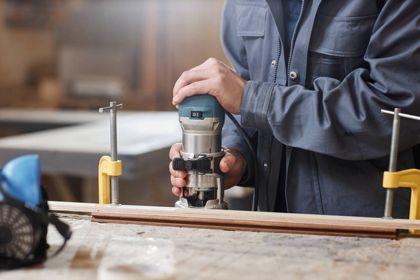 Primer plano del trabajador masculino irreconocible que corta madera con la herramienta eléctrica en taller de la fábrica, espacio de la copia - Foto, Imagen