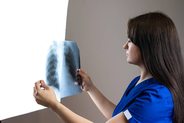 Kaukasische Ärztin untersucht Röntgenlungen in der Klinik. Gesundheitswesen, medizinische Berufe - Foto, Bild