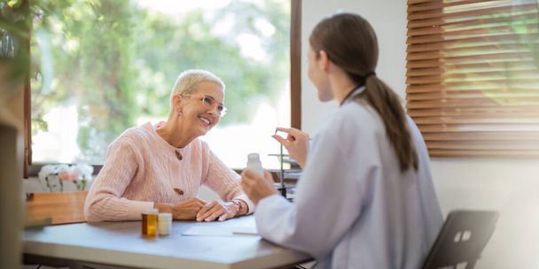 ιατρική συζήτηση αποτελέσματα ή συμπτώματα και δίνει συμβουλές σχετικά με την ιατρική σε μια ηλικιωμένη γυναίκα ασθενή, δίνοντας συμβουλές κατά τη διάρκεια της ιατρικής εξέτασης στην κλινική. - Φωτογραφία, εικόνα