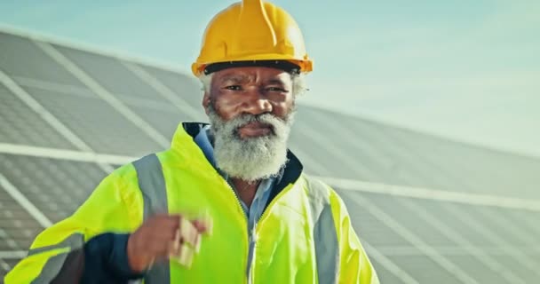 Senior engineer man, solar panel and helmet with smile, greeting and face for sustainability in nature. Photovoltaic renewable energy, African technician or portrait for electricity, ecology or power. - Footage, Video