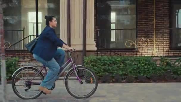 Donna caucasica in giacca e cravatta che va in bicicletta in ufficio. Trasporto ecologico in città, la ragazza ha fretta per un incontro d'affari. Filmati 4k di alta qualità - Filmati, video