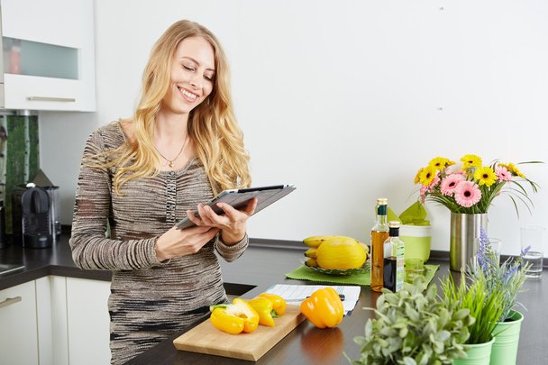 Blonde woman using a tablet computer to cook - Fotó, kép