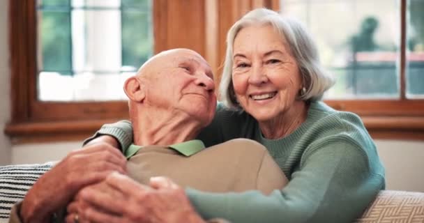 Поцелуи, лицо и пожилая пара в доме на диване, счастливы и связаны вместе в гостиной. Смит, влюбленные пожилые мужчина и женщина, здоровые отношения и романтические связи, забота и объятия. - Кадры, видео
