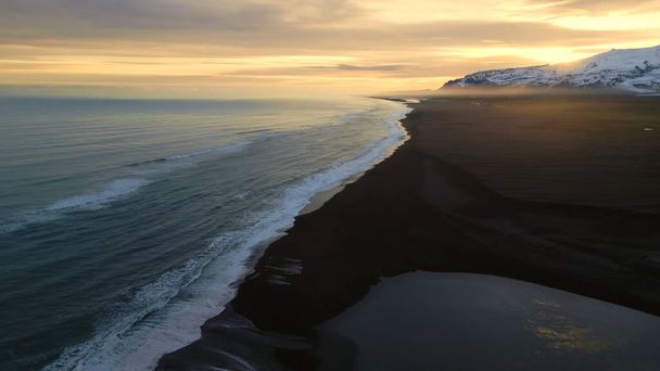 Atlanic tengerpart fekete homokos strand hullámok összeomlik jégen partján, gyönyörű természeti táj Iszkandországban. Drónfelvétel fenséges festői útvonalról és skandináv tájról. Lassú mozgás.. - Fotó, kép