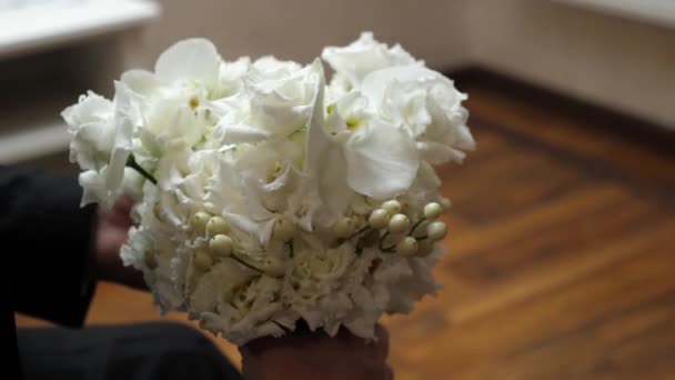 Lo sposo tiene in mano un bellissimo bouquet da sposa bianco. cerimonia nuziale. - Filmati, video