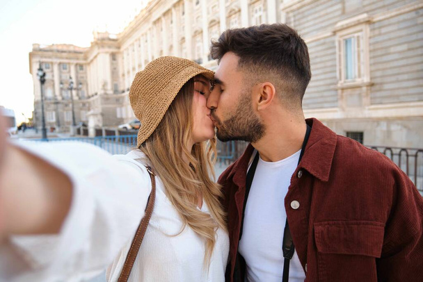 Young Caucasian couple taking a selfie while kissing and sightseeing the city of Madrid, Spain. - Photo, Image