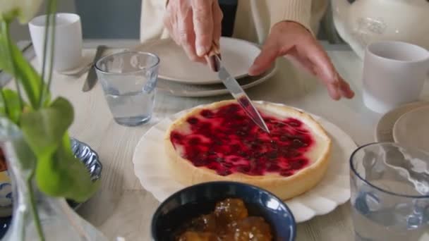 Vystřižený záběr rukou starší babičky krájení domácí bobule dort u jídelního stolu - Záběry, video
