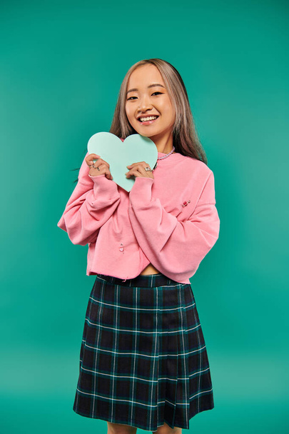 Happy Valentijnsdag, vrolijke aziatische vrouw met hartvormige doos op turquoise achtergrond - Foto, afbeelding