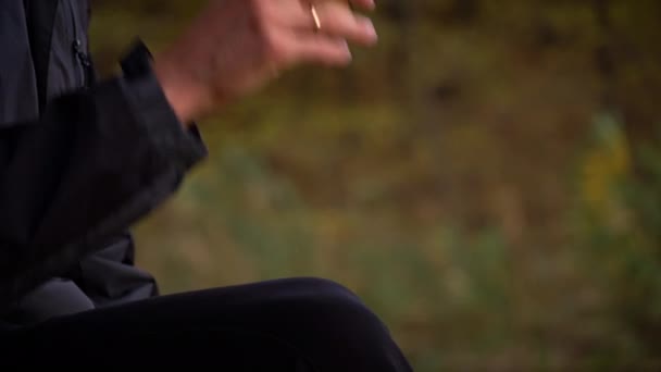 Male hands take a glass of coffee close-up in the autumn atmosphere. A young guy drinks coffee while walking in the park. Life style. Autumn walks concept. - Footage, Video